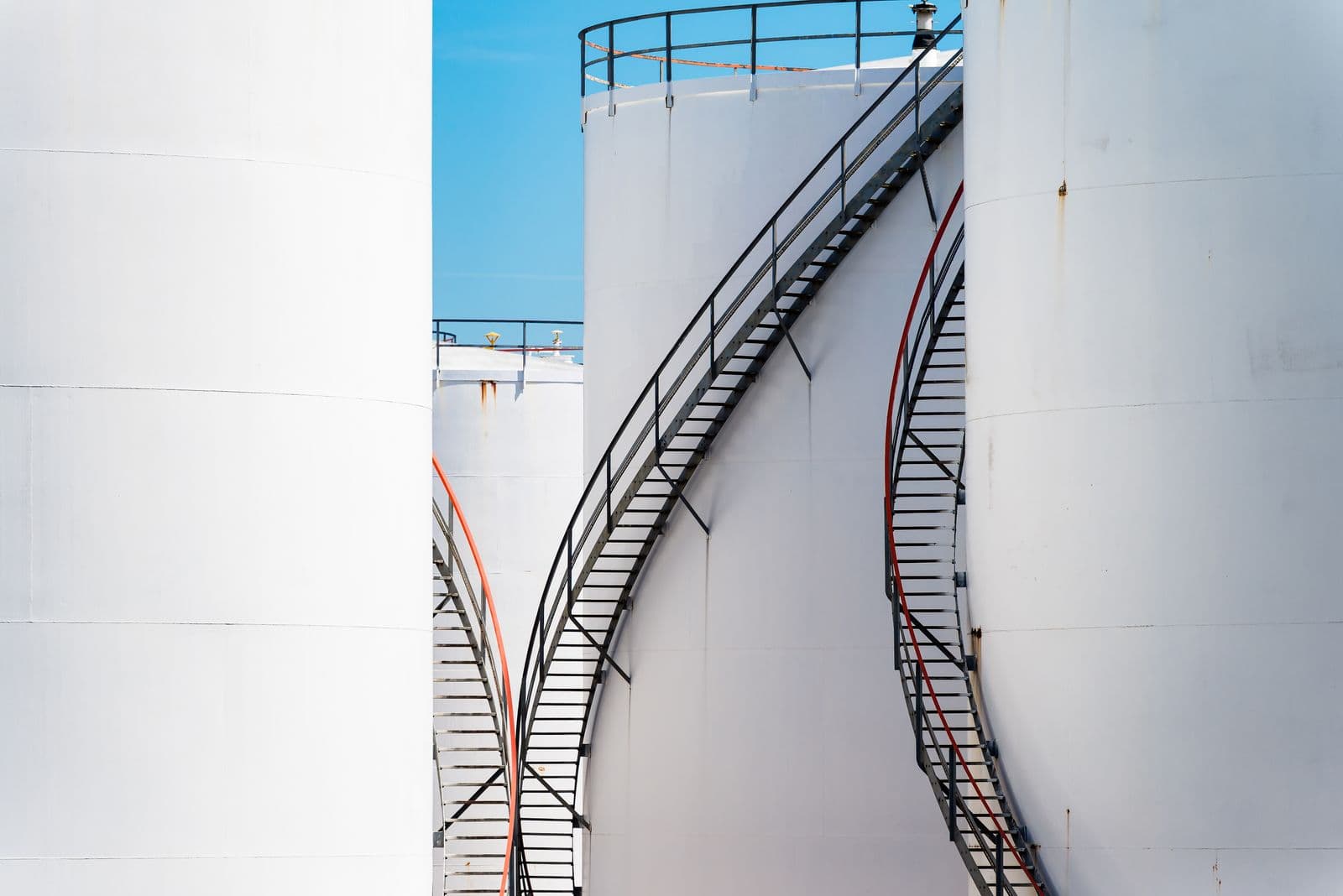 Aboveground white oil storage tanks with external access stairs at a fuel storage site.